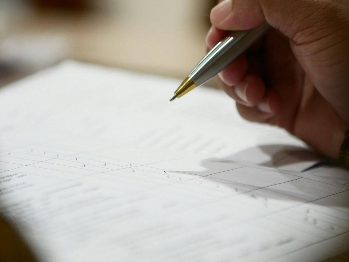 Hand holding a pen signing a closing document